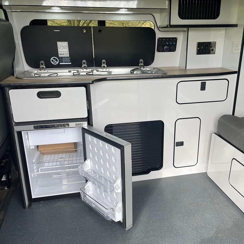 White gloss camper kitchen with hob, sink and fridge